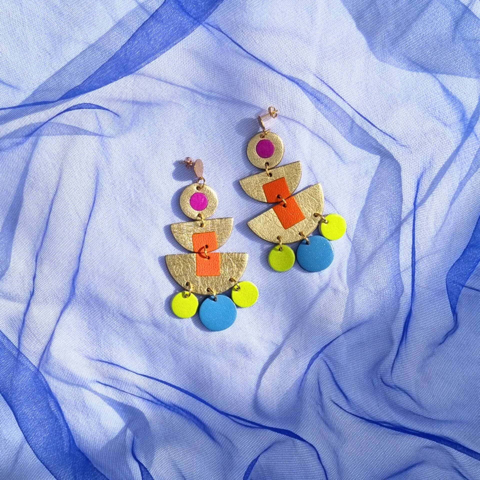 Statement earrings with pink and orange inlayed into gold leather with yellow and blue accent circles by The Hummingbird Archives